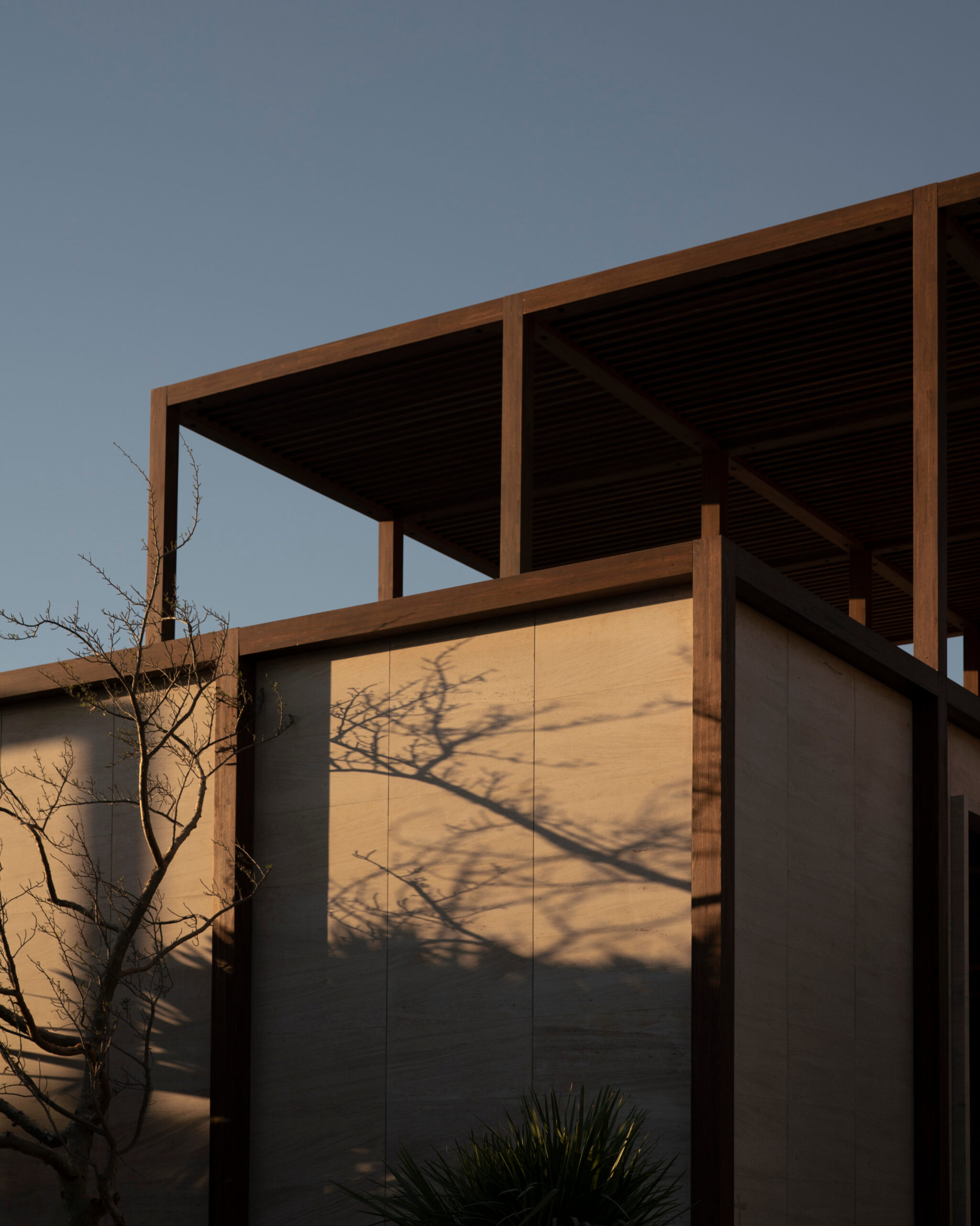 Steel canopy frames and rammed earth walls at dusk at Ánima Village, Los Cabos. By Sordo Madaleno.