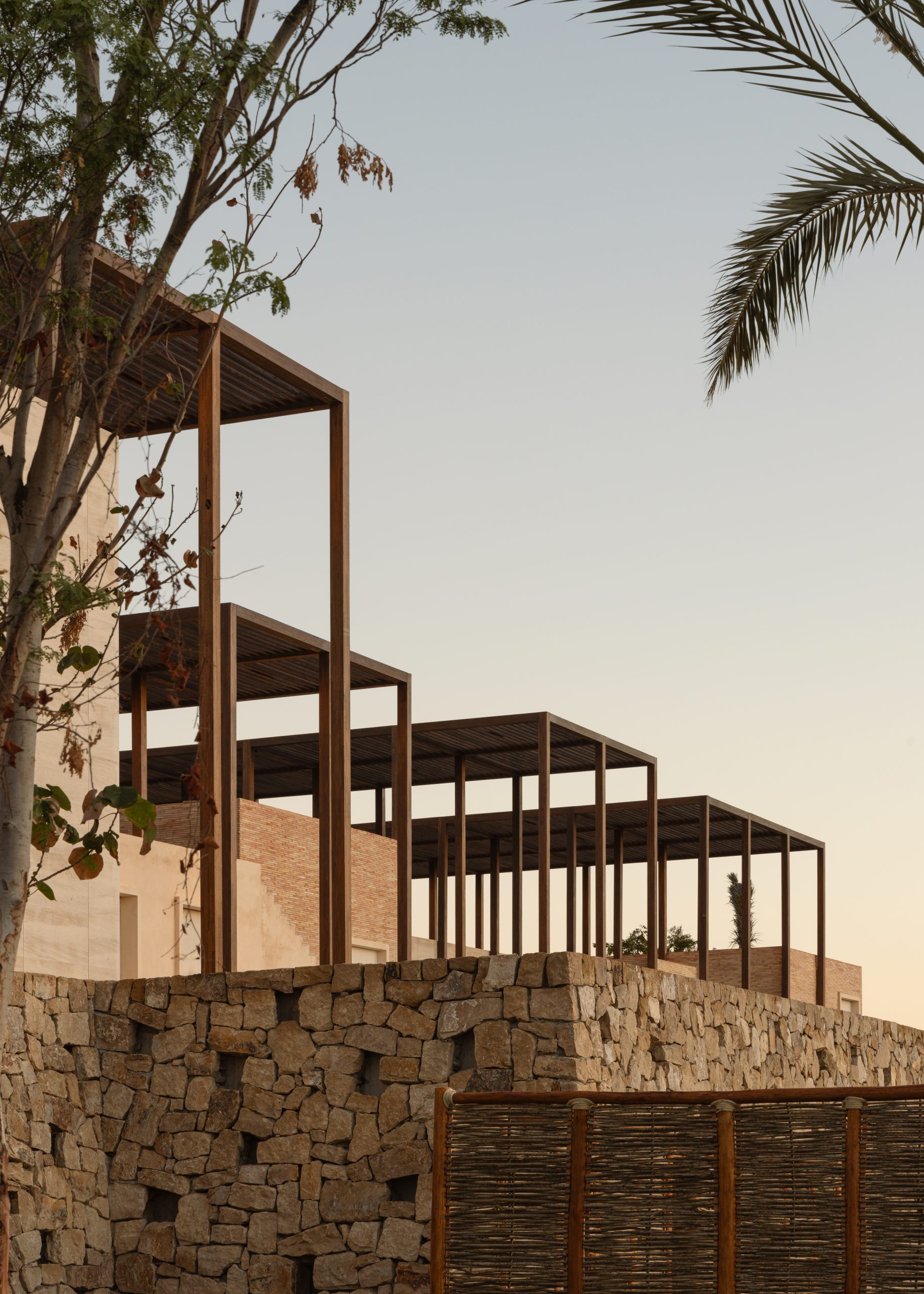 Stepped steel pergolas and stone base at Ánima Village open-air retail district, Los Cabos. By Sordo Madaleno.