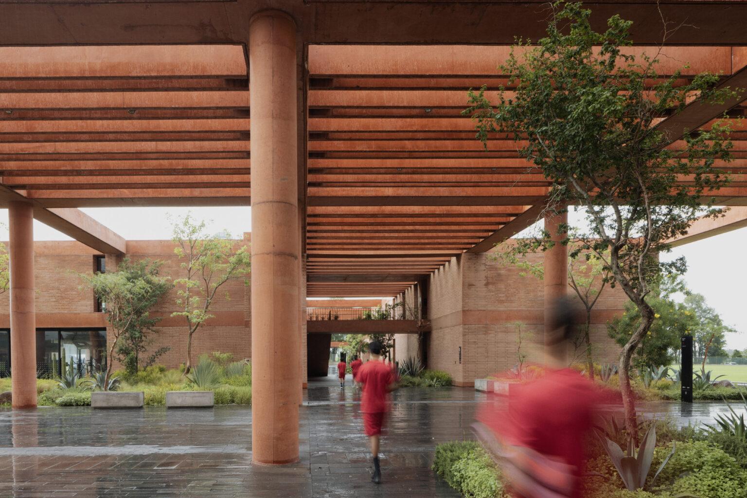 Sordo Madaleno — Covered terracotta colonnade and planted courtyard at Academia Atlas football training campus, Guadalajara. By Sordo Madaleno.