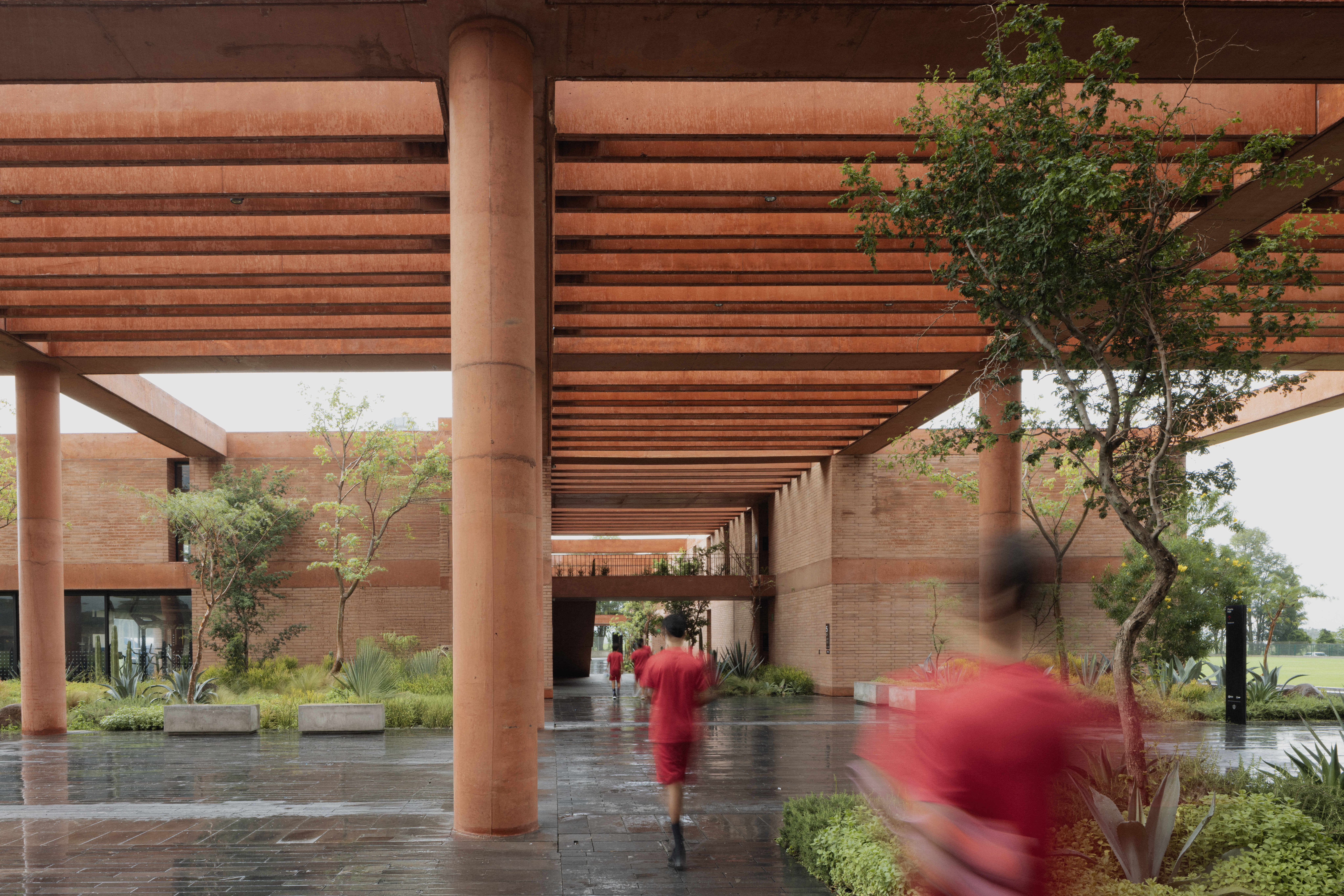 Covered terracotta colonnade and planted courtyard at Academia Atlas football training campus, Guadalajara. By Sordo Madaleno.