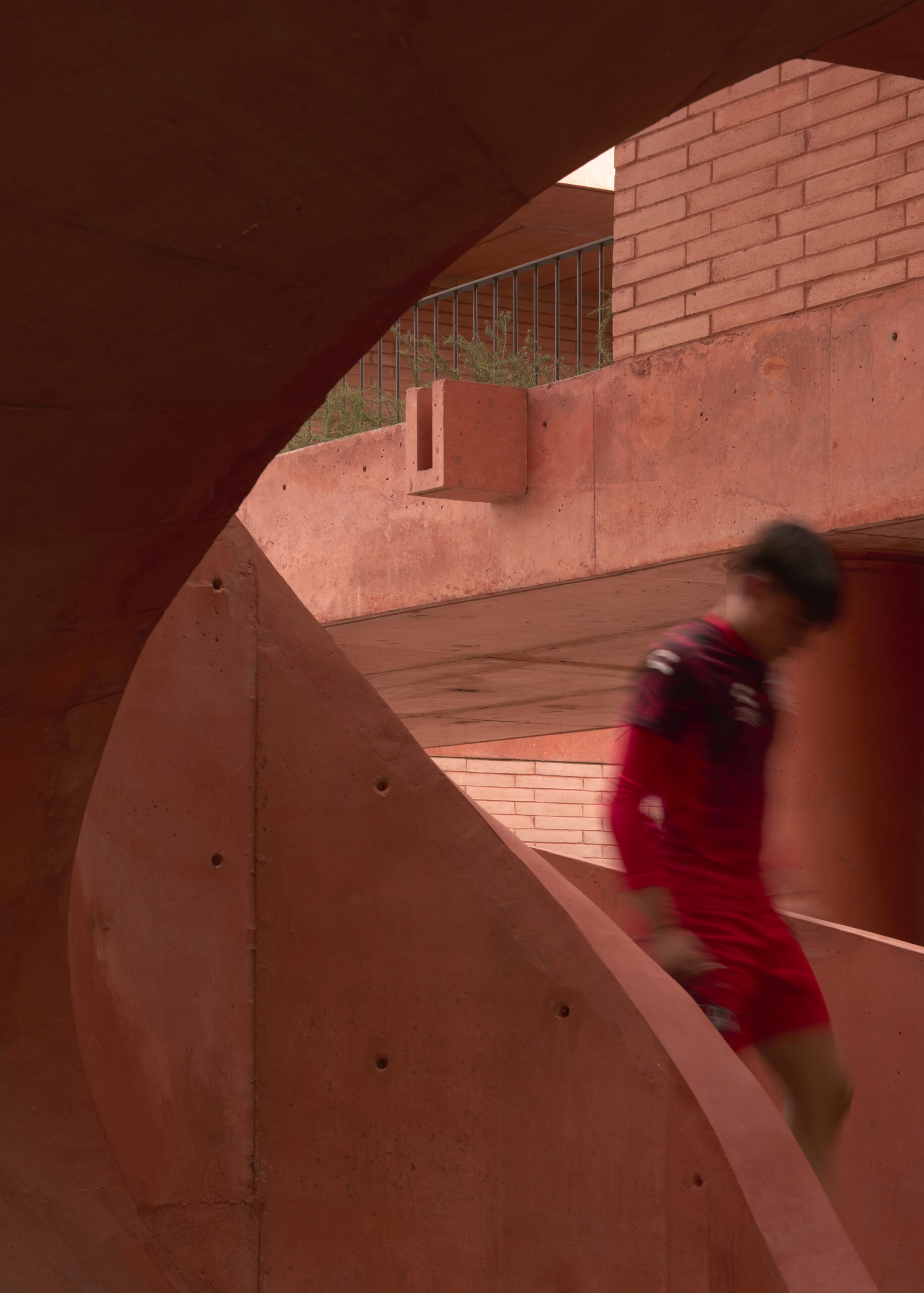 Atlas FC player ascending a curved concrete staircase at Academia Atlas training campus, Guadalajara. By Sordo Madaleno.