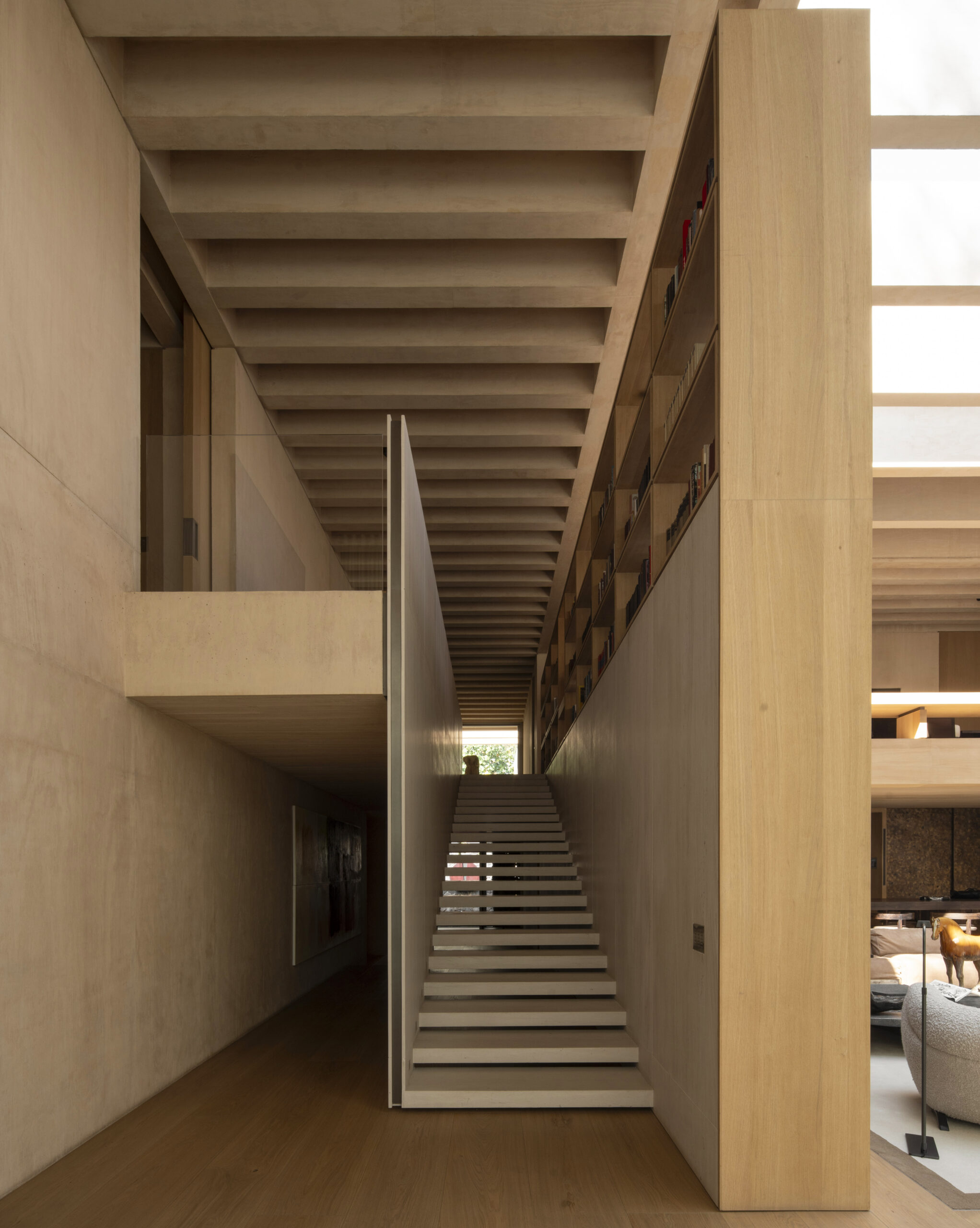 Double-height timber library staircase at Casa SM, a three-generation modernist family home in Mexico City. By Sordo Madaleno.