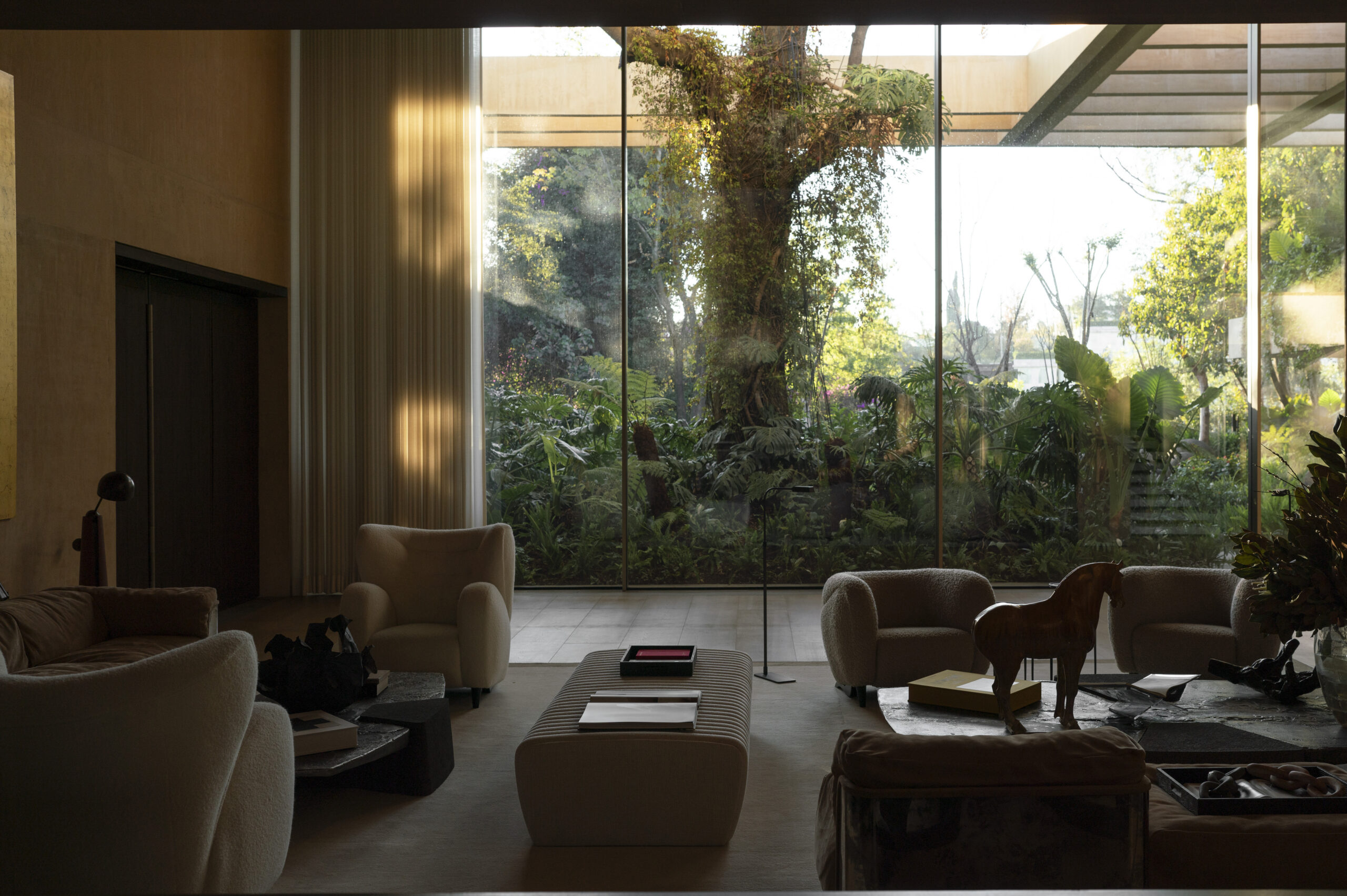 Living room with full-height glazing overlooking the lush garden and ash tree at Casa SM, Mexico City. By Sordo Madaleno.