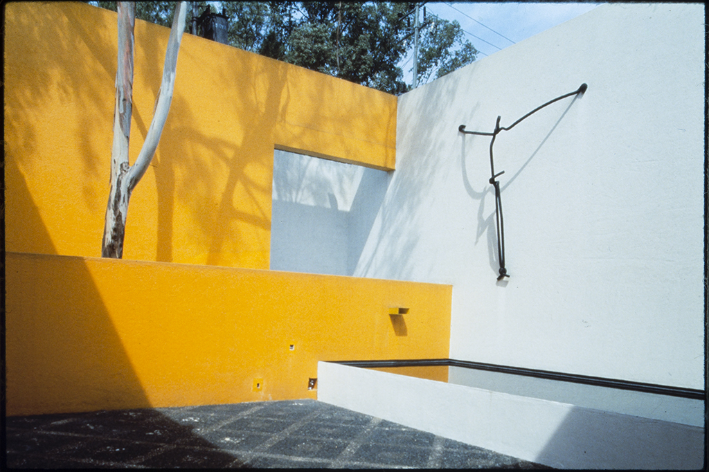 Metal Christ, a sculpture by Mathias Goeritz on a white wall next to a bright yellow wall