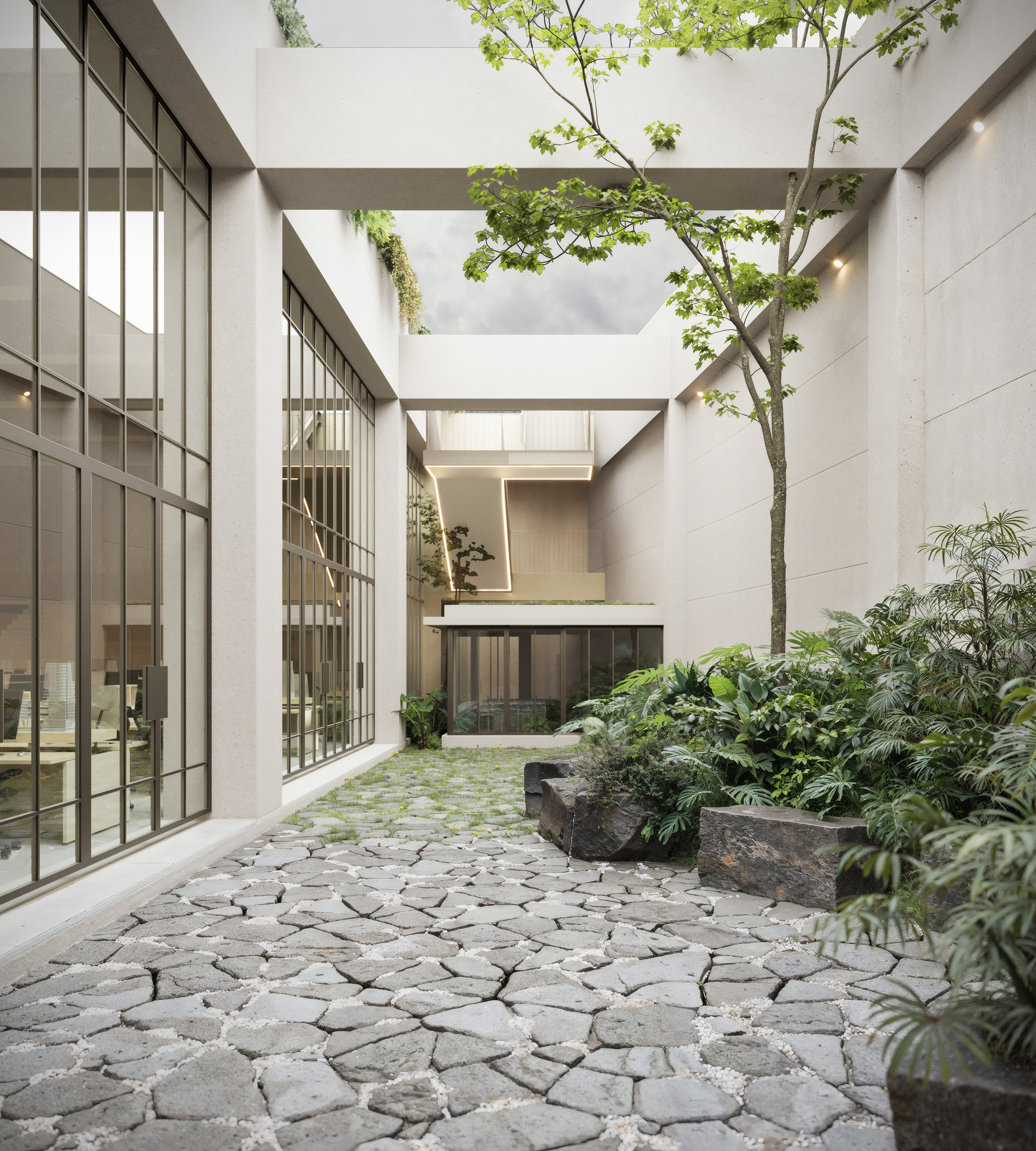 Jardín interior del Corporativo Soma, con Piedra volcánica, exuberantes parterres y fachadas acristaladas de altura completa que se abren al paisaje interior.