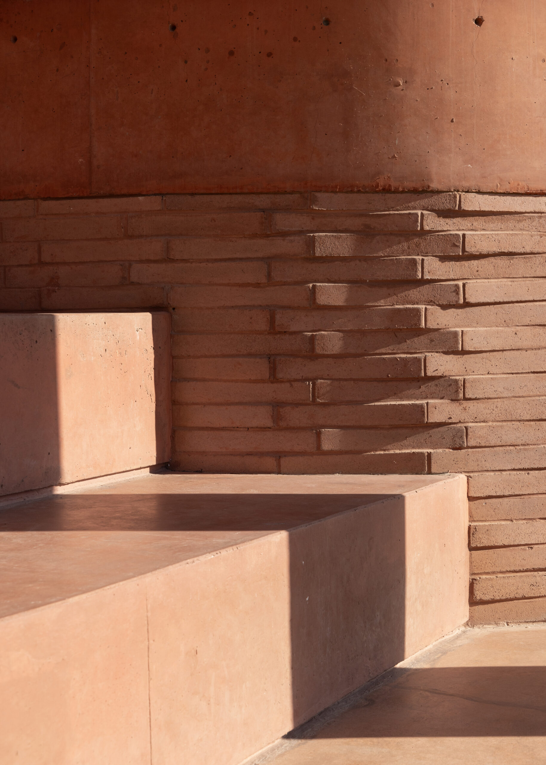 Exposed brick and pigmented concrete, stepped seating detail — Academia Atlas