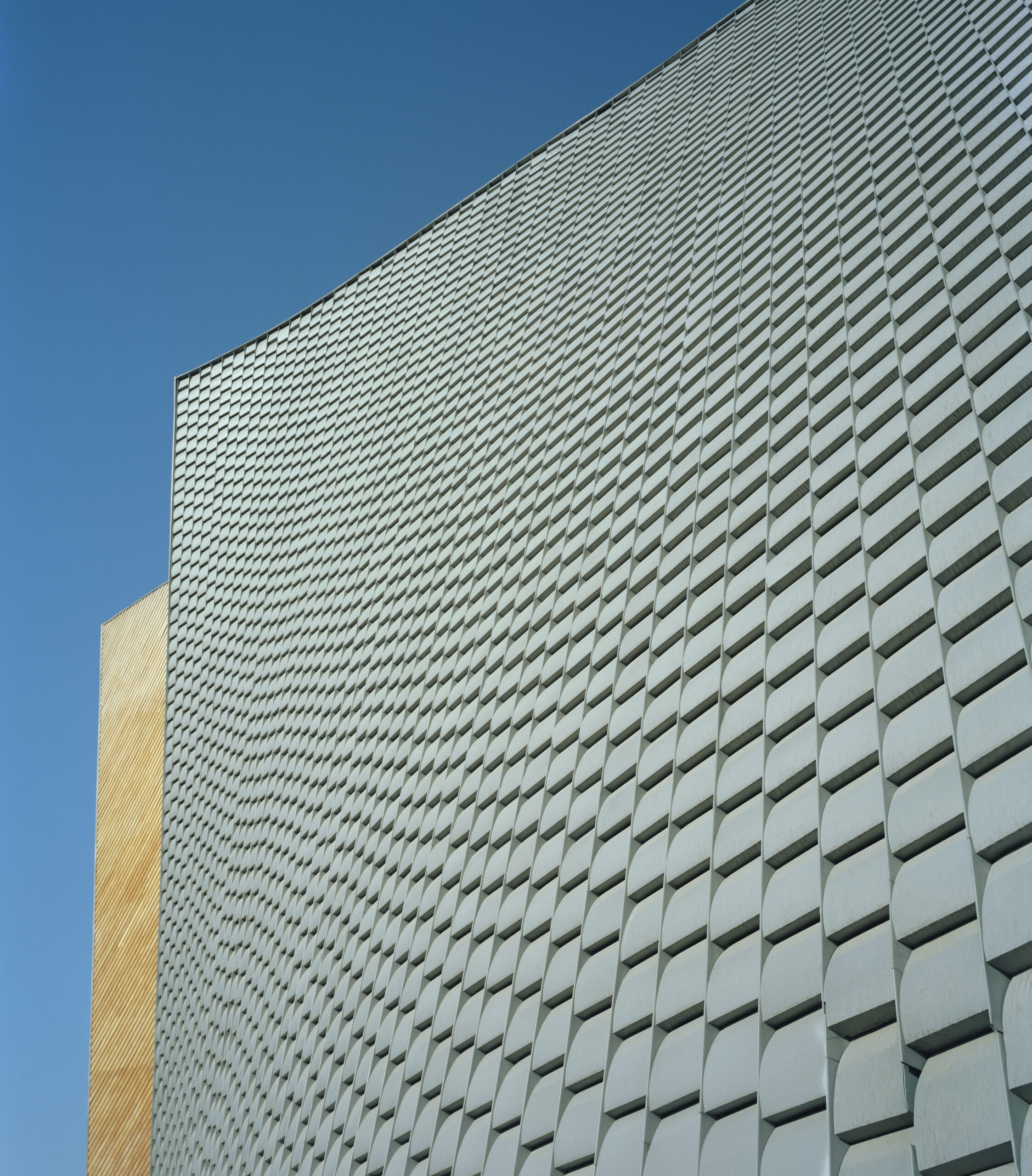 Primer plano del revestimiento de láminas de zinc en la fachada curva de la iglesia de San Josemaría Escrivá, en Santa Fe, Ciudad de México. Obra de Sordo Madaleno.