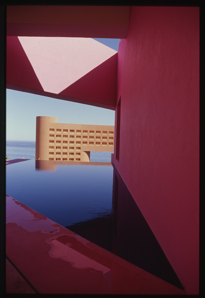 Fotografía de archivo de la piscina y la torre curvada del hotel Westin Regina Los Cabos, enmarcadas por paredes de un rojo intenso y con vistas al mar de Cortés, 1993. Sordo Madaleno.
