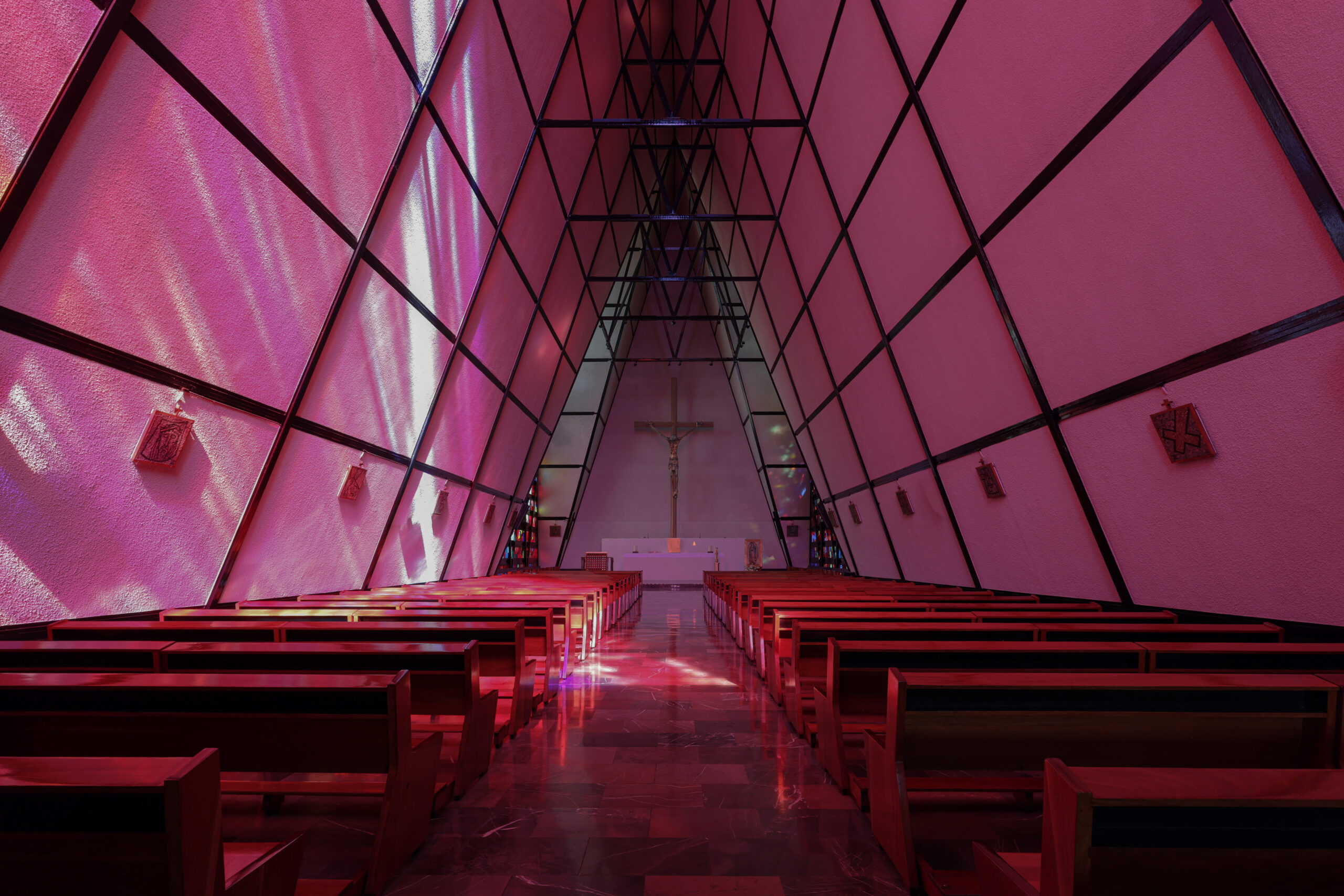 Interior nave of San Ignacio de Loyola Church bathed in pink light through stained glass walls, Polanco, Mexico City. Juan Sordo Madaleno, 1961.