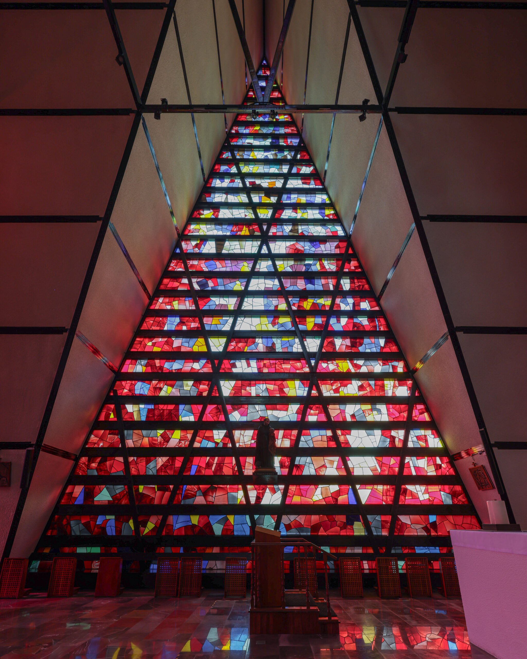 Floor-to-ceiling stained glass triangular window flooding the interior of San Ignacio de Loyola Church with colour, Polanco. Juan Sordo Madaleno, 1961.