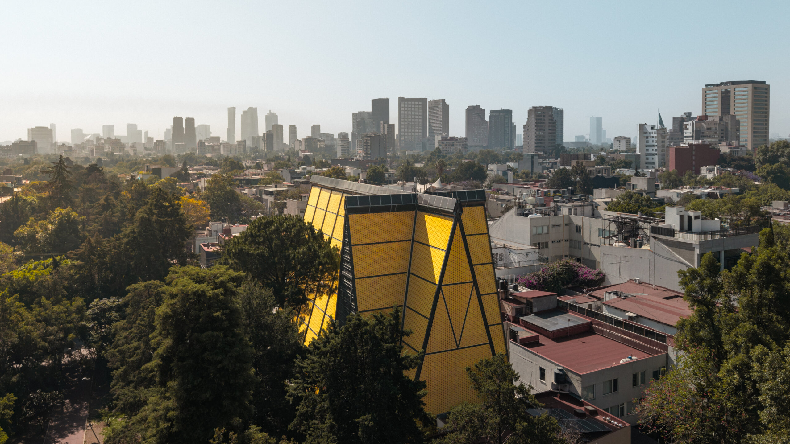 Aerial view of San Ignacio de Loyola Church's yellow ceramic triangular form above Polanco, Mexico City skyline beyond. Juan Sordo Madaleno, 1961.