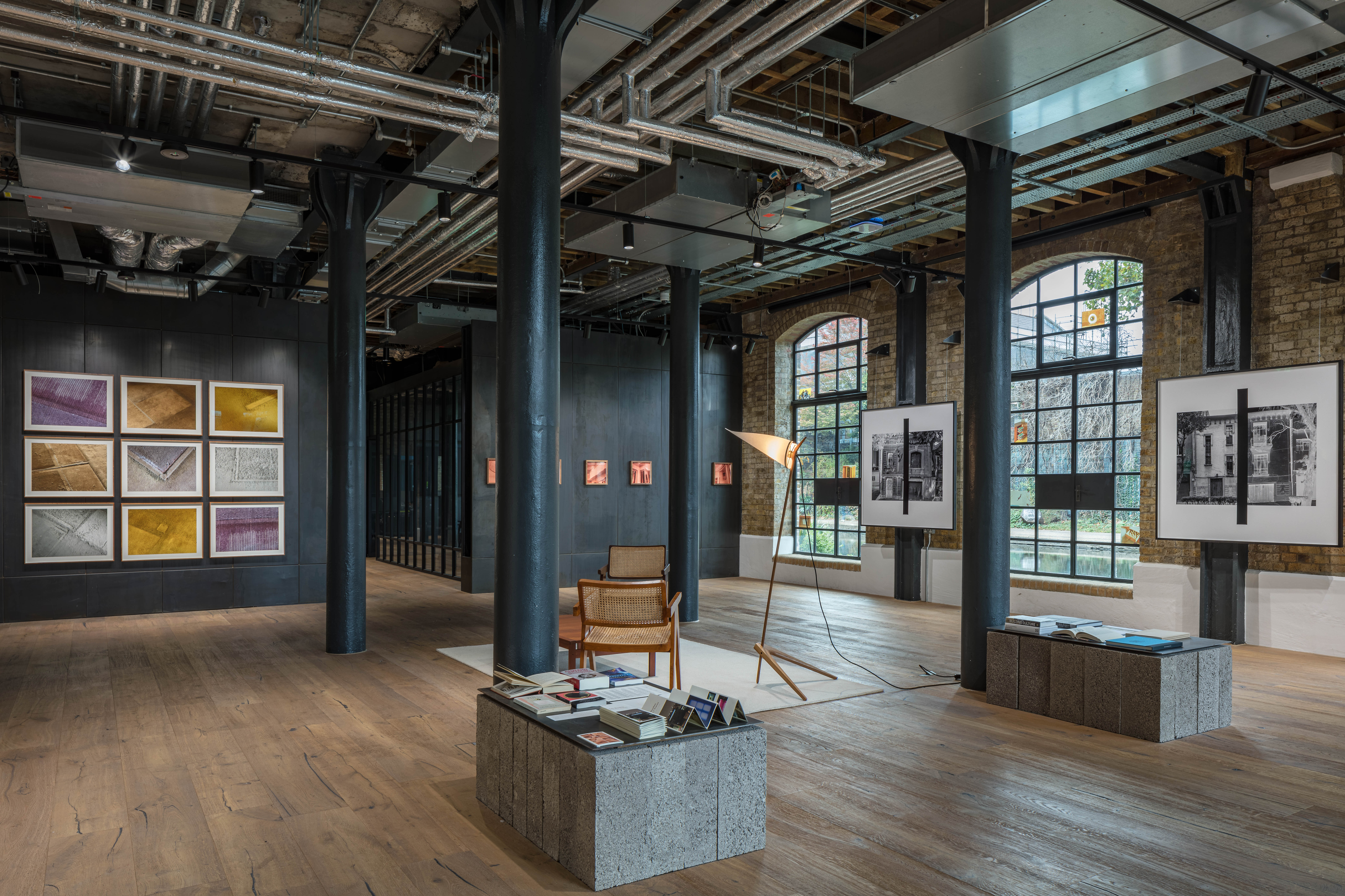 Places/Traces exhibition at Obra, London: coloured photograph grid, black-and-white facade prints and cane chairs beside arched canal windows